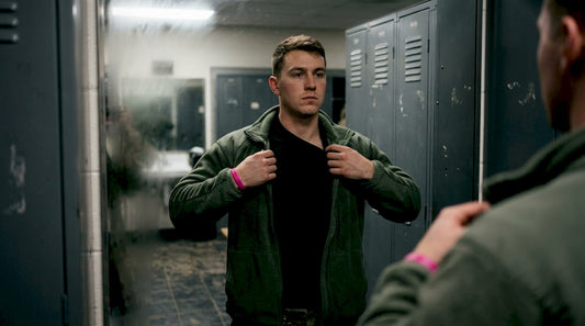 Soldier putting on moisture-wicking base layer in locker room