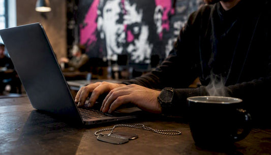 Hands verifying military status online with laptop and dog tag