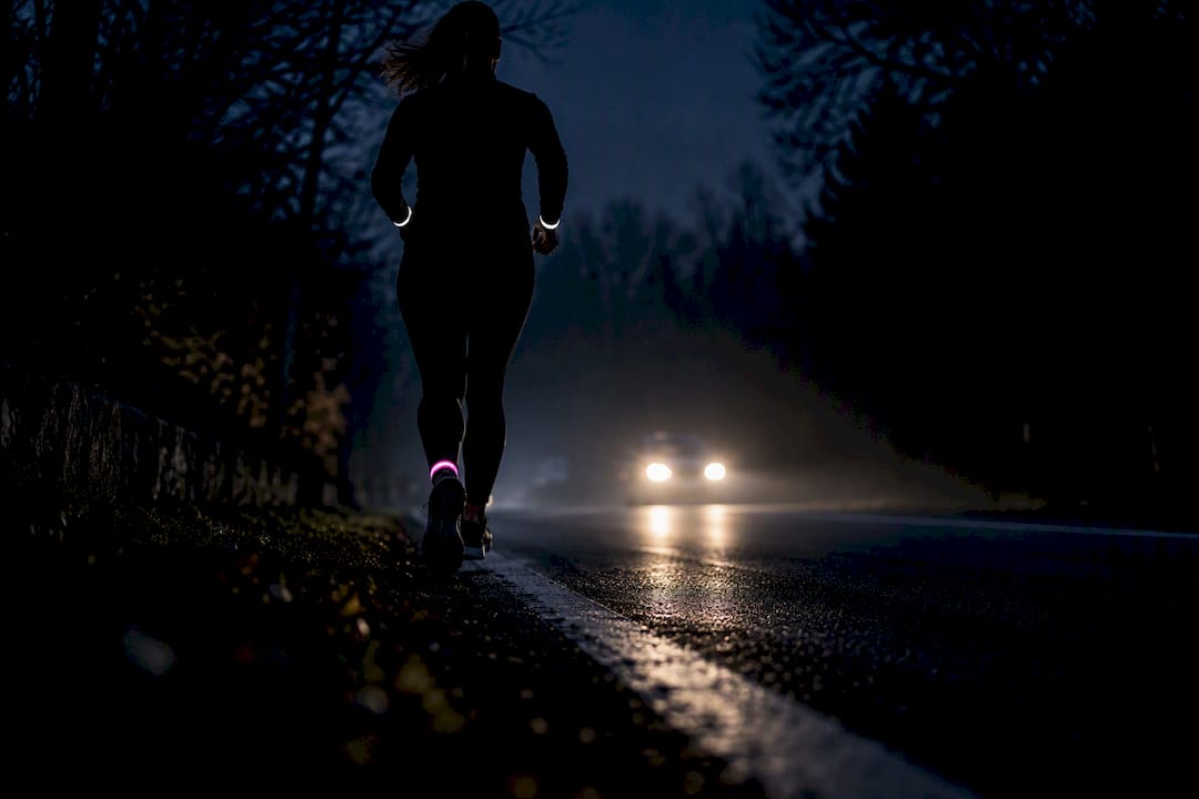 Runner illuminated by headlights at night