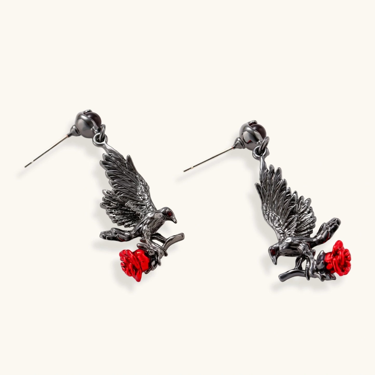 Dark gunmetal raven earrings with red rose details, featuring detailed bird wings and S925 silver posts on cream background.
