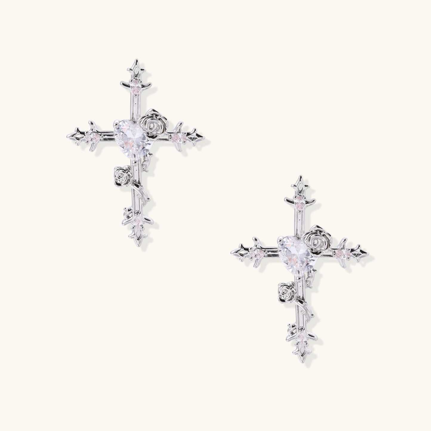 Ornate gold-plated cross earrings with zirconia stones and rose details on neutral background.